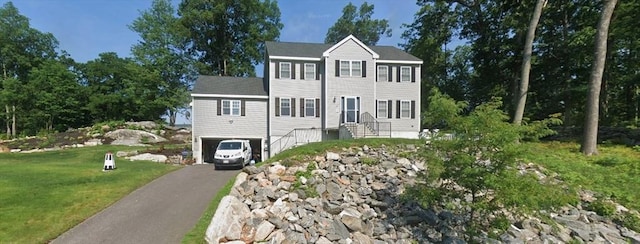 colonial inspired home featuring entry steps, a front lawn, an attached garage, and driveway