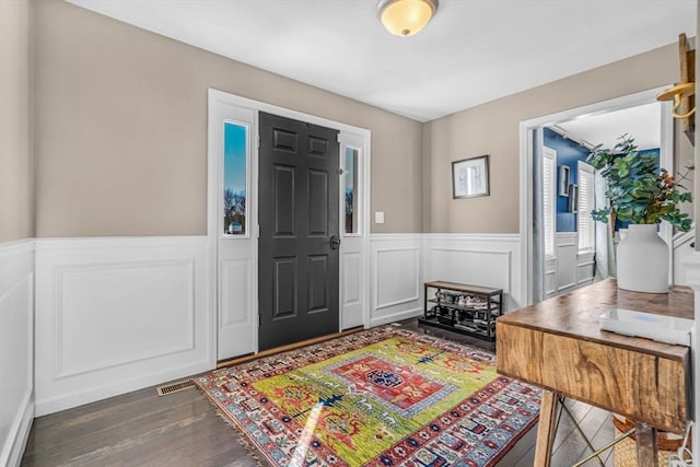 foyer with a wainscoted wall, visible vents, and wood finished floors