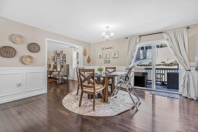 dining space featuring a notable chandelier, a wainscoted wall, and hardwood / wood-style floors