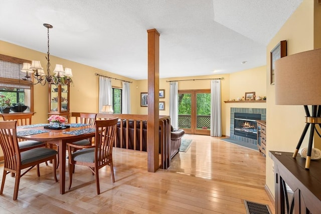 25 Ash Ln Unit 25, Agawam, MA 01001 - dining area with a tiled fireplace, light wood-style floors, a chandelier, and a textured ceiling