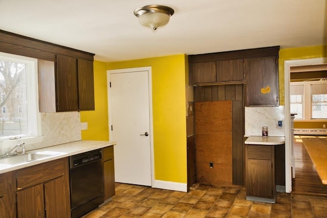 kitchen with backsplash, black dishwasher, light countertops, and a sink