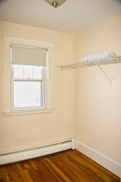 spacious closet featuring a baseboard heating unit and dark wood finished floors