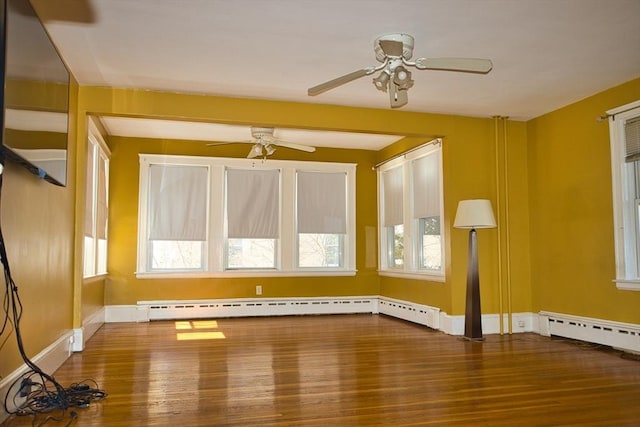 interior space with a baseboard heating unit, ceiling fan, baseboards, and wood finished floors