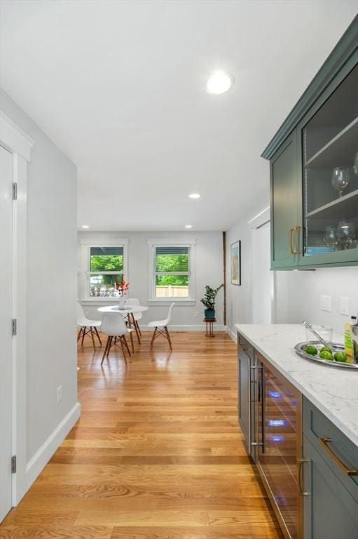84 S St, Rockport, MA 01966 - kitchen with light wood-type flooring, wine cooler, light stone countertops, recessed lighting, and glass insert cabinets