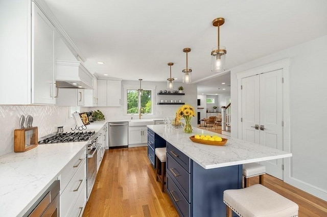 84 S St, Rockport, MA 01966 - kitchen with stainless steel appliances, white cabinetry, custom exhaust hood, light wood-type flooring, and a breakfast bar