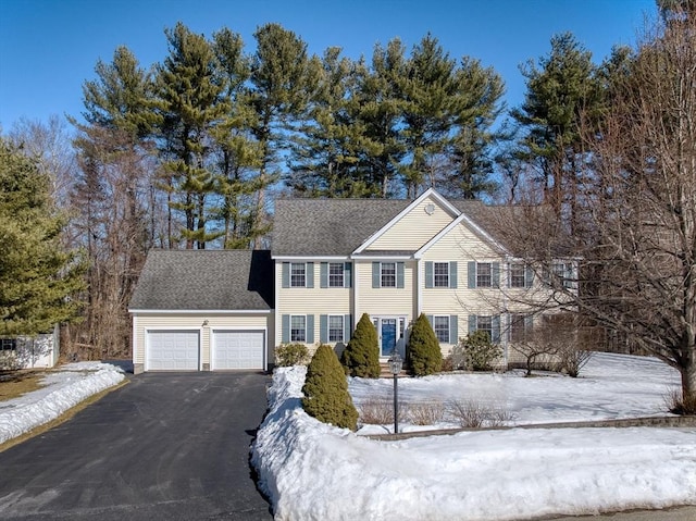 colonial home with a garage, driveway, and a shingled roof