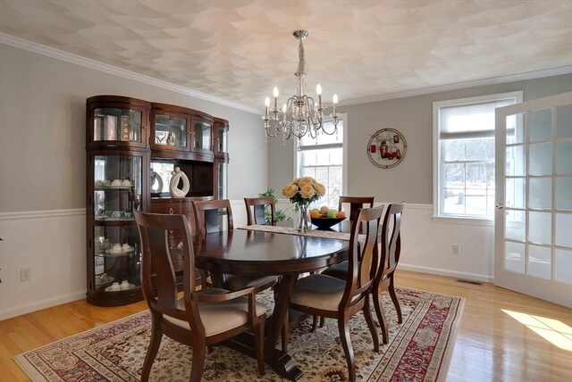 dining room featuring light wood-style flooring, baseboards, and crown molding