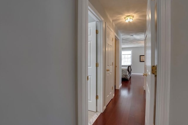 corridor with baseboards and wood finished floors