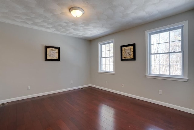 spare room featuring baseboards and dark wood-style flooring