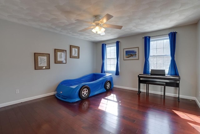 bedroom with multiple windows, baseboards, and wood finished floors