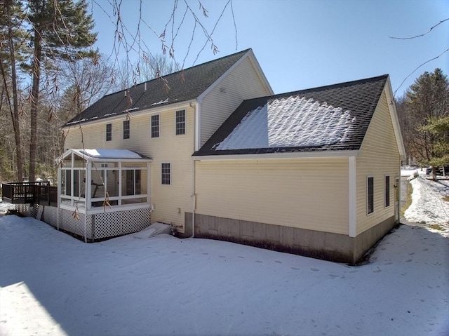 snow covered house featuring a sunroom