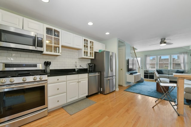 kitchen featuring decorative backsplash, white cabinetry, stainless steel appliances, and light hardwood / wood-style floors