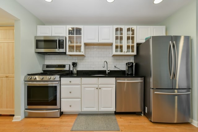 kitchen with sink, light hardwood / wood-style flooring, stainless steel appliances, and white cabinets