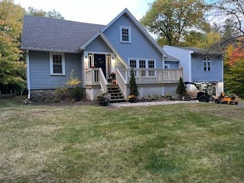 view of front of house with a wooden deck and a front yard