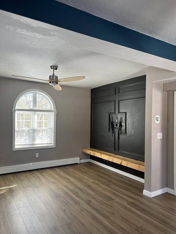 interior space featuring ceiling fan, dark hardwood / wood-style floors, a textured ceiling, and baseboard heating