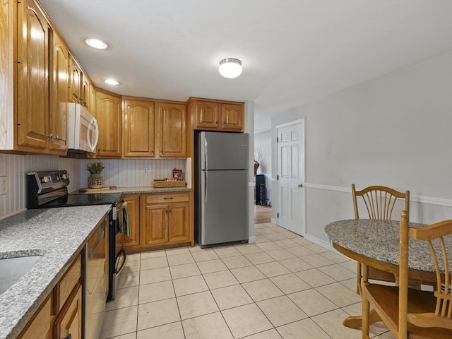 kitchen featuring appliances with stainless steel finishes, brown cabinets, and light tile patterned flooring