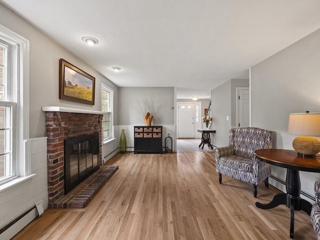 sitting room with a baseboard radiator, a fireplace, and light wood finished floors