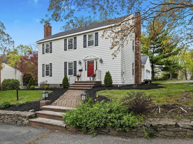 colonial house with a chimney and a front yard
