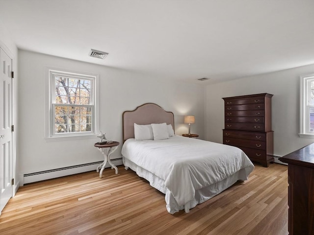 bedroom featuring multiple windows, a baseboard heating unit, and visible vents