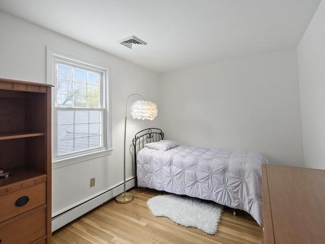 bedroom featuring visible vents, wood finished floors, and baseboard heating