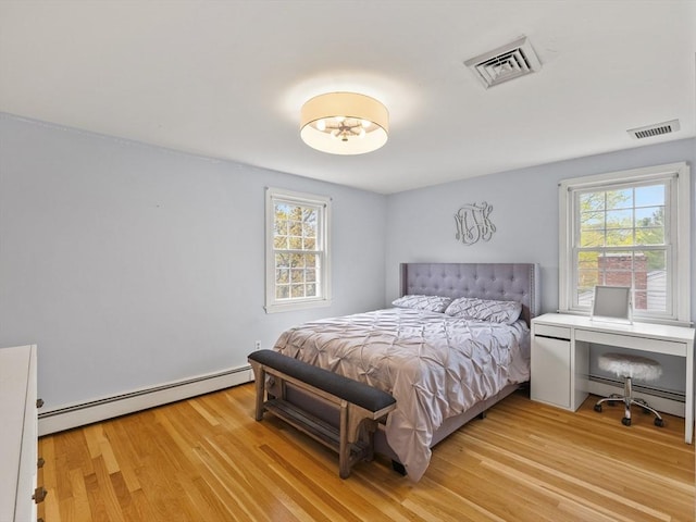 bedroom with baseboard heating, light wood-style flooring, and visible vents