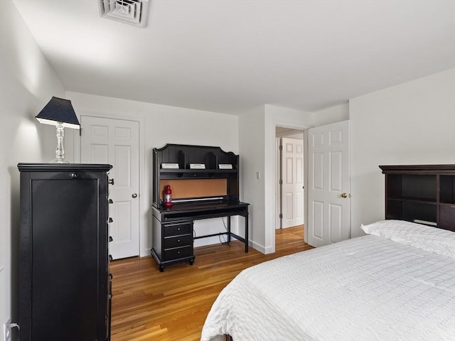 bedroom with visible vents, baseboards, and wood finished floors