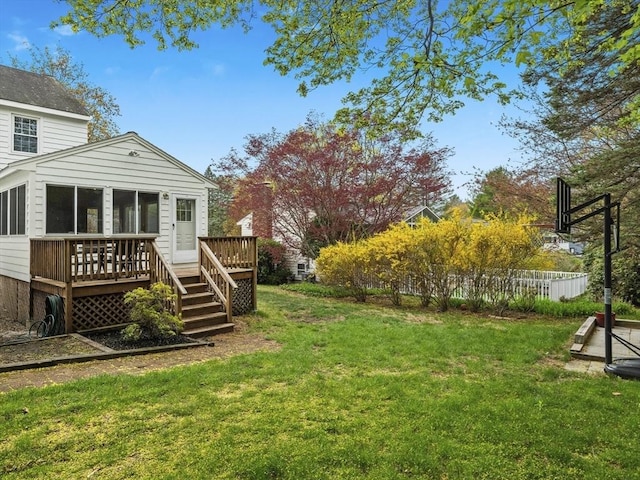 view of yard featuring fence, a wooden deck, and a sunroom