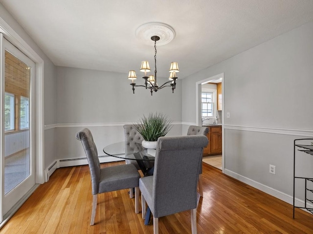 dining area with baseboards, an inviting chandelier, plenty of natural light, and light wood-type flooring