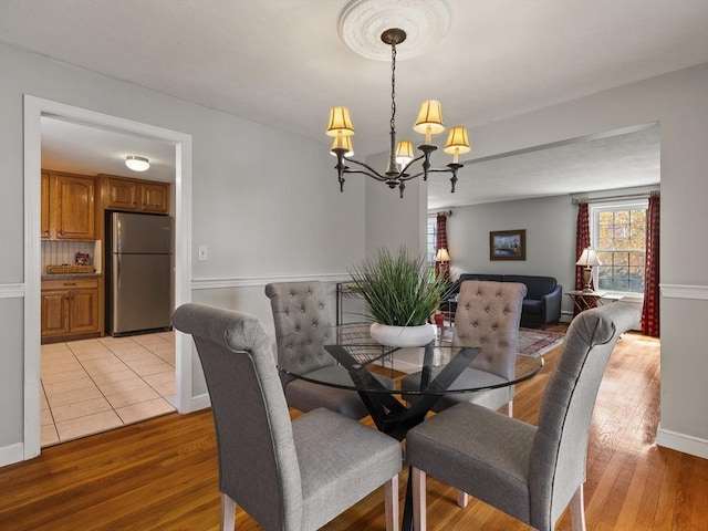 dining room featuring an inviting chandelier, baseboards, and light wood-type flooring
