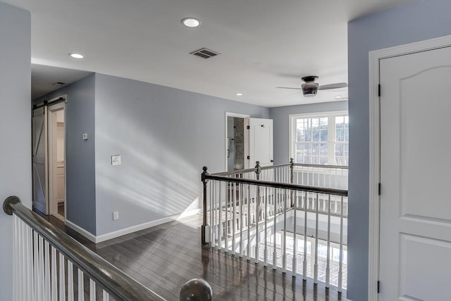 corridor with dark hardwood / wood-style floors and a barn door