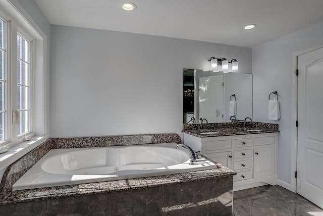 bathroom featuring vanity, tiled tub, and a healthy amount of sunlight