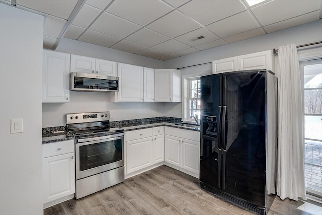 kitchen featuring appliances with stainless steel finishes, sink, white cabinets, and light hardwood / wood-style flooring