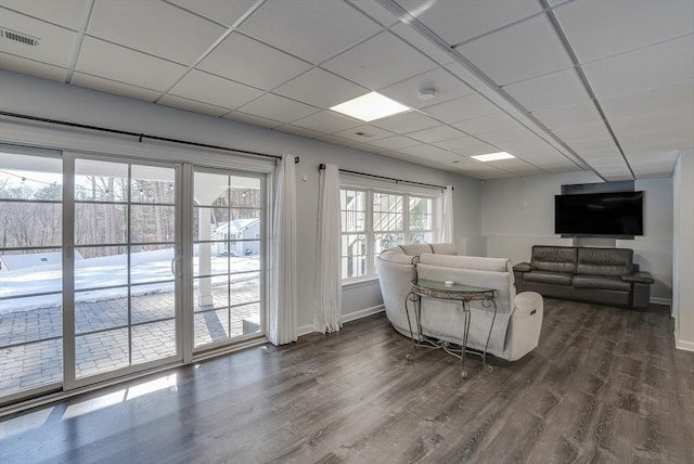 living room with dark wood-type flooring and a drop ceiling