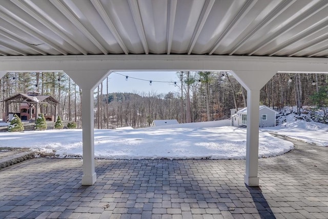 snow covered patio featuring a storage shed