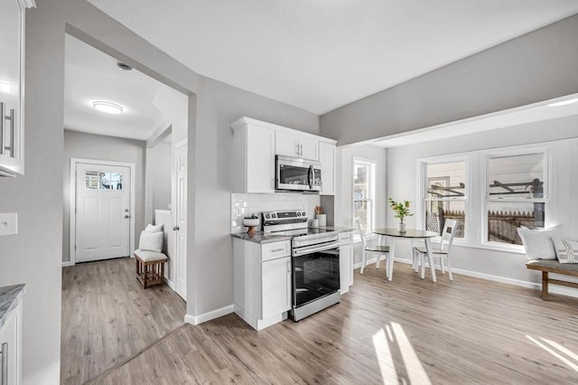 kitchen with white cabinets, light hardwood / wood-style floors, stainless steel appliances, and tasteful backsplash