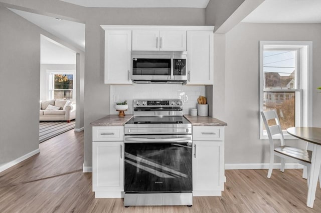 kitchen with plenty of natural light, white cabinetry, stainless steel appliances, and light hardwood / wood-style flooring