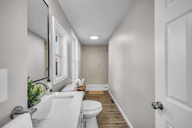 bathroom with a shower, hardwood / wood-style floors, vanity, and toilet