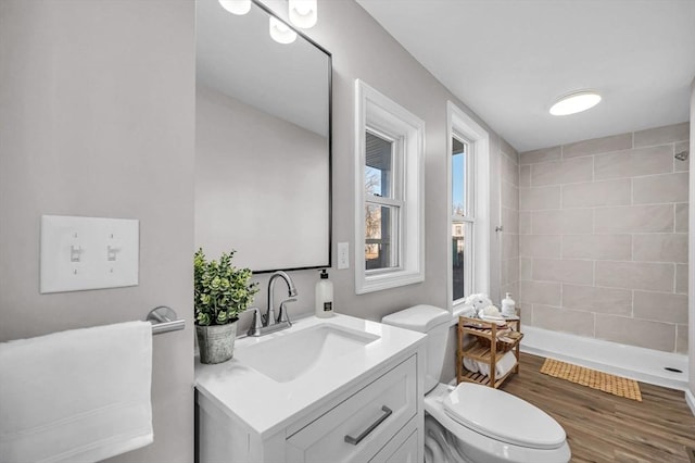 bathroom featuring hardwood / wood-style flooring, toilet, vanity, and walk in shower