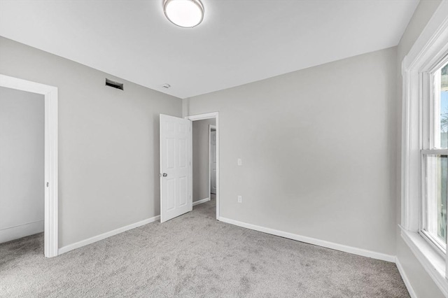 unfurnished bedroom featuring light carpet and a closet