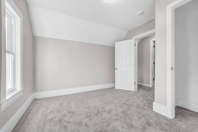 additional living space featuring light colored carpet and lofted ceiling