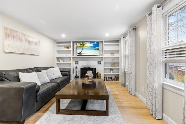 living area featuring recessed lighting, light wood-type flooring, baseboards, and a brick fireplace