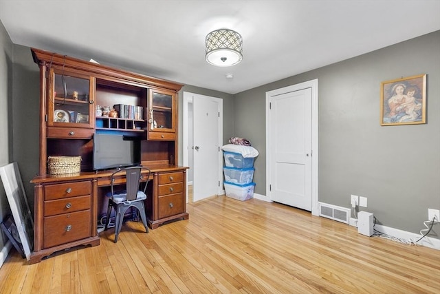 office space featuring baseboards, visible vents, and light wood finished floors