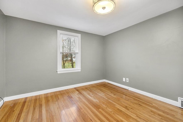 empty room with visible vents, baseboards, and hardwood / wood-style flooring