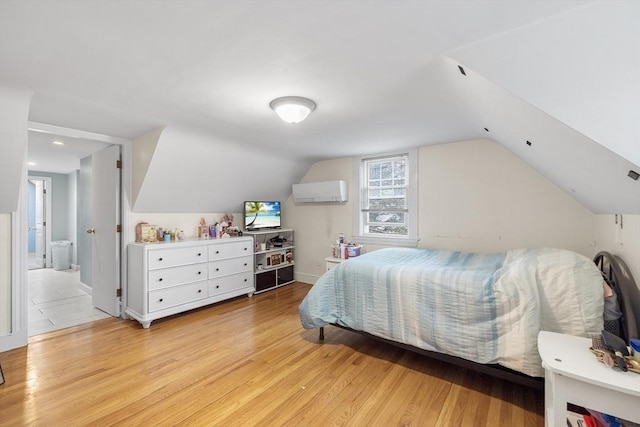 bedroom with lofted ceiling, an AC wall unit, baseboards, and light wood-type flooring