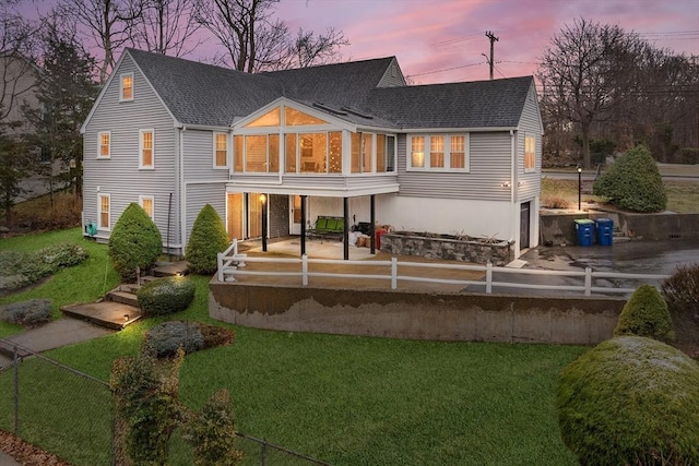 rear view of property with a lawn, a shingled roof, and a patio