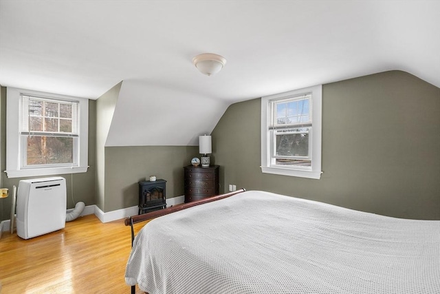 bedroom featuring lofted ceiling, multiple windows, wood finished floors, and baseboards