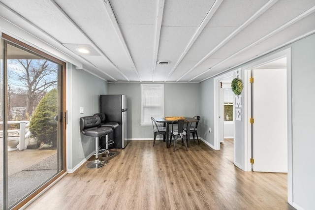 dining room featuring light wood finished floors, visible vents, and baseboards