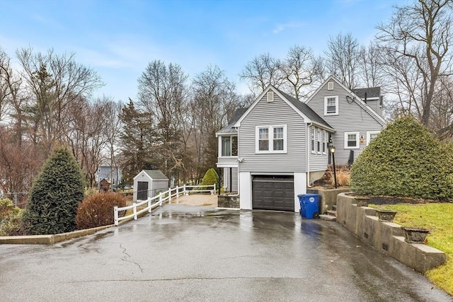 view of front of property with aphalt driveway, an attached garage, and fence