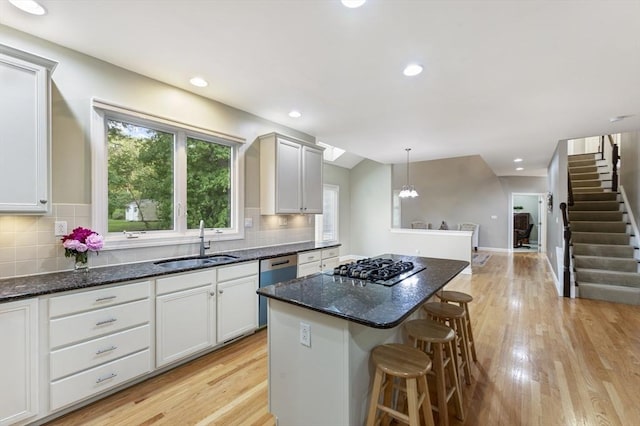 138 Fairview St, Holliston, MA 01746 - kitchen featuring a center island, stainless steel dishwasher, a kitchen bar, light wood finished floors, and decorative backsplash