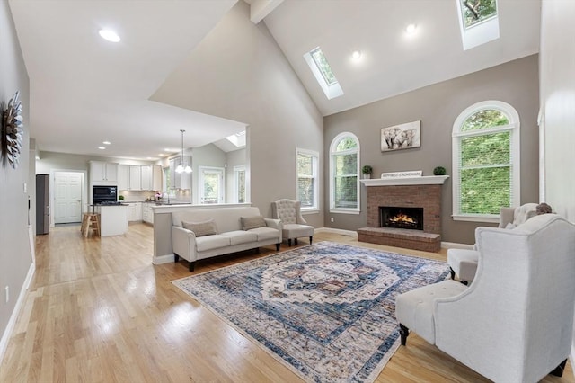 138 Fairview St, Holliston, MA 01746 - living room with a skylight, a brick fireplace, light wood-style flooring, high vaulted ceiling, and recessed lighting